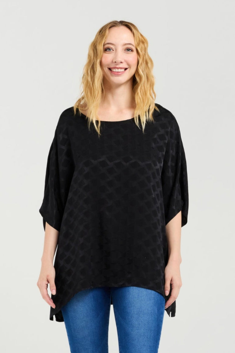 Woman wearing a black patterned top and blue jeans on a white background