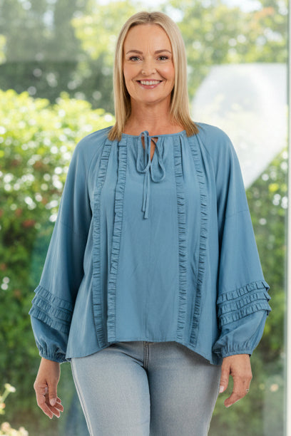 Woman wearing a blue denim top and jeans on a white background
