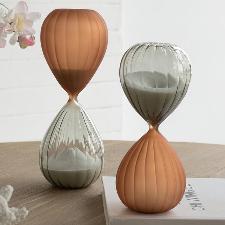 Two hourglass-shaped vases on a wooden surface with a blurred background
