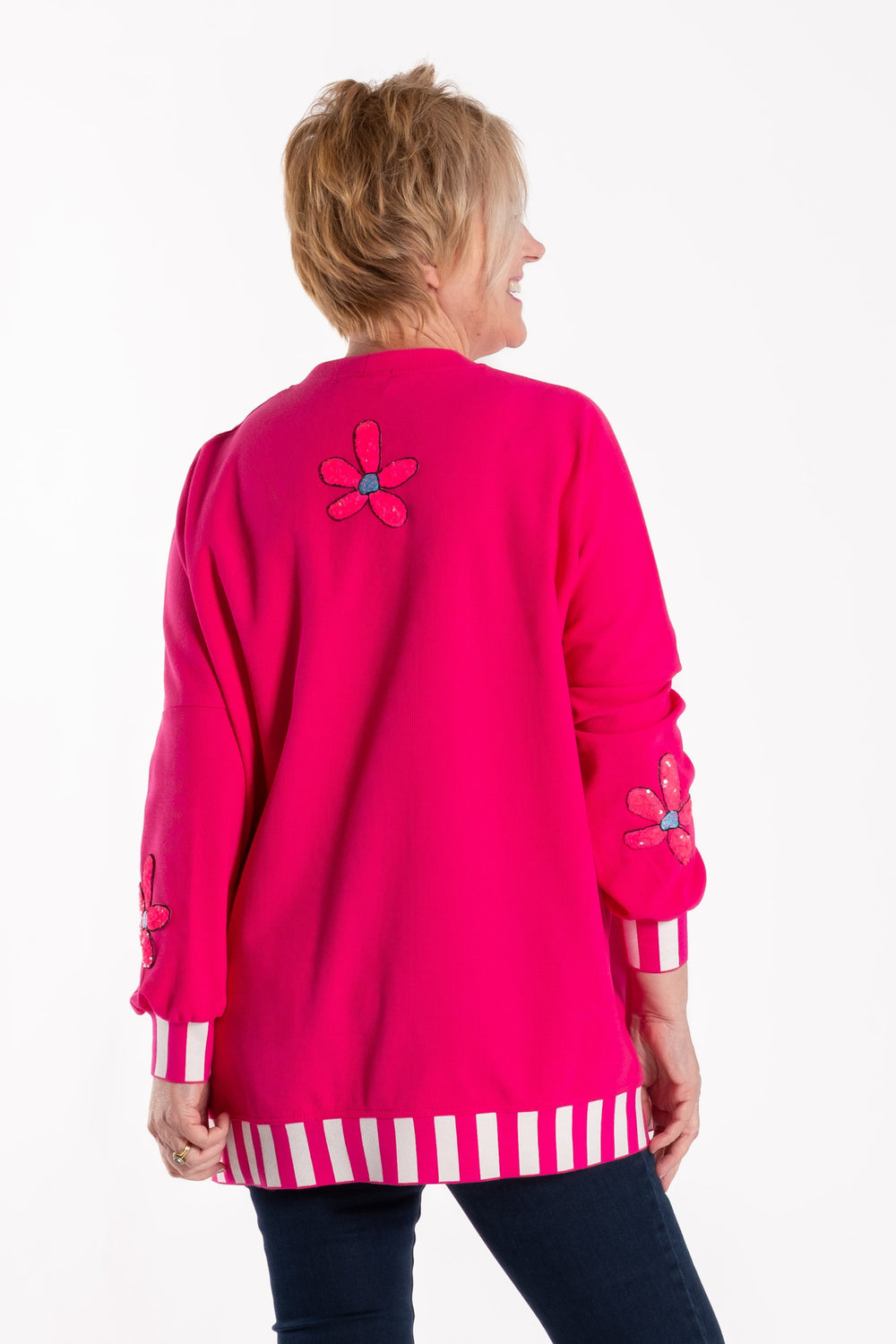 Person wearing a bright pink sweater with a butterfly design on a white background