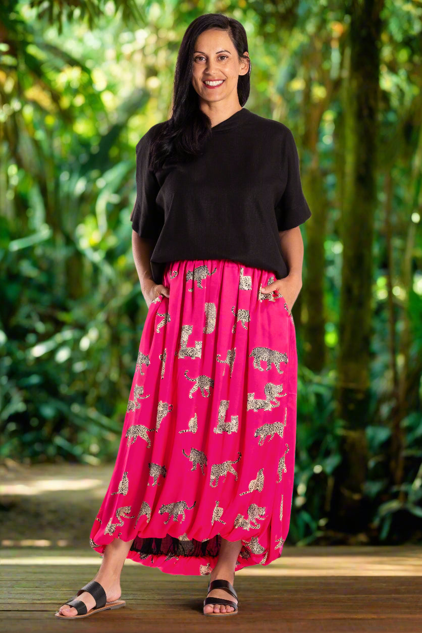 Woman wearing a black top and pink skirt with elephant pattern on a white background