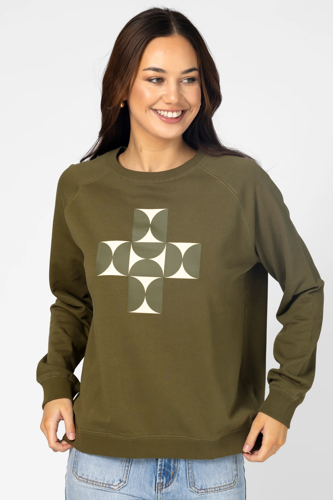 Woman wearing an olive green sweatshirt with a geometric design on a white background