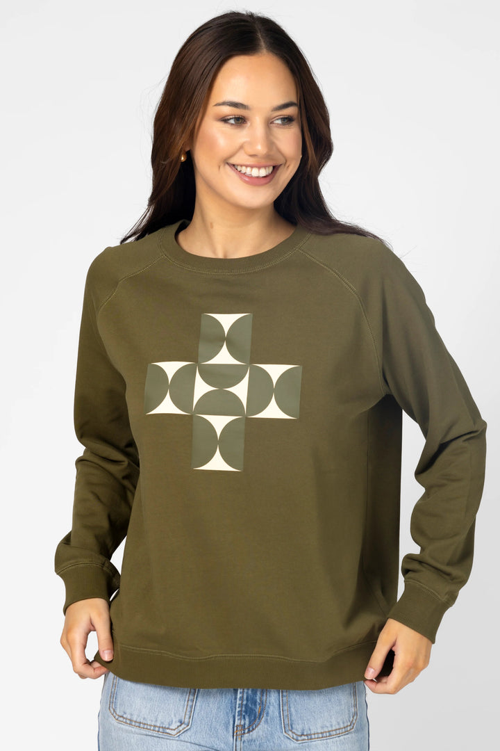 Woman wearing an olive green sweatshirt with a geometric design on a white background