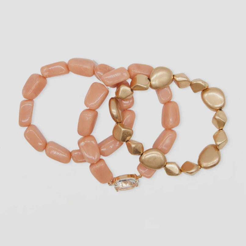 Set of three beaded bracelets with pink and gold stones on a light gray background