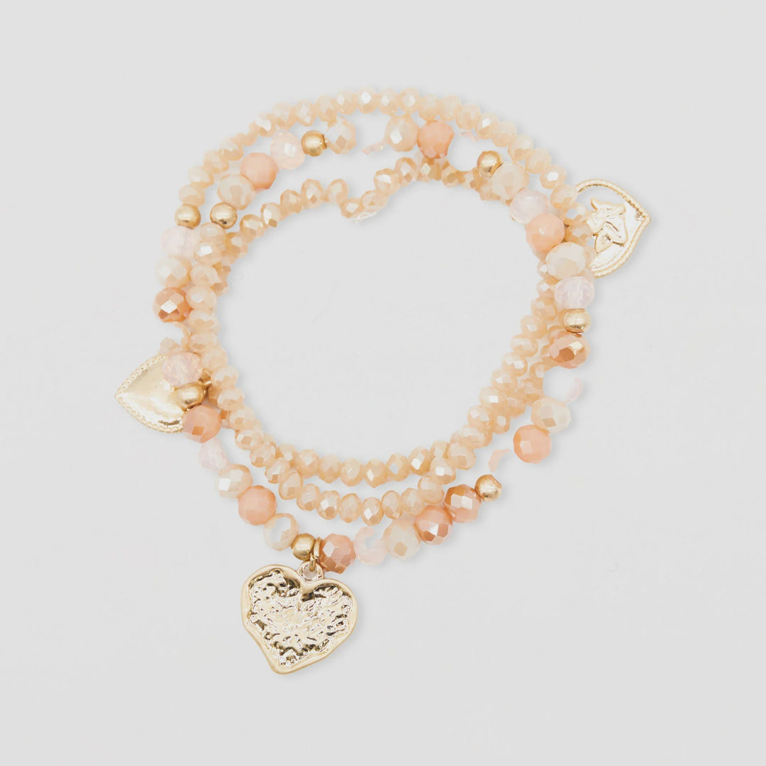 Stack of pink beaded bracelets with heart charms on a light gray background