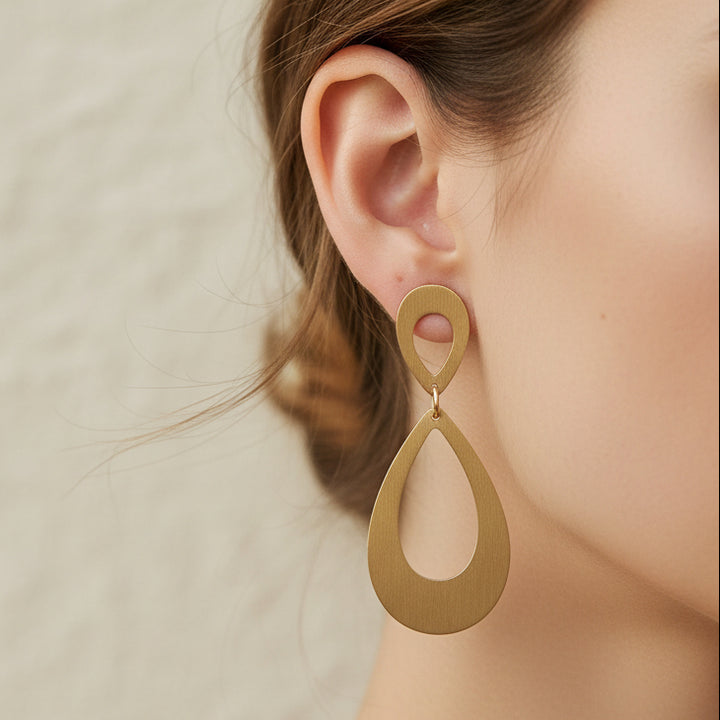 Gold teardrop earrings on a light gray background