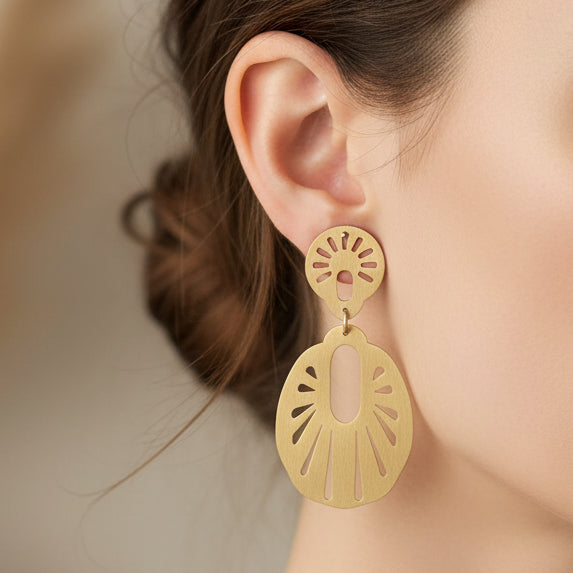 Gold earrings on a light gray background