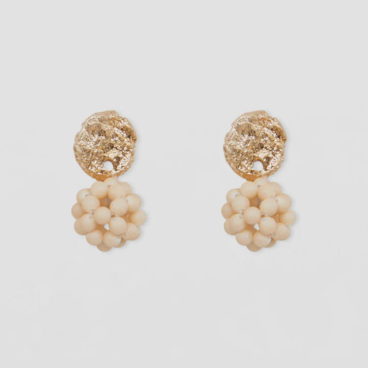 Pair of earrings with gold and beige elements on a light background