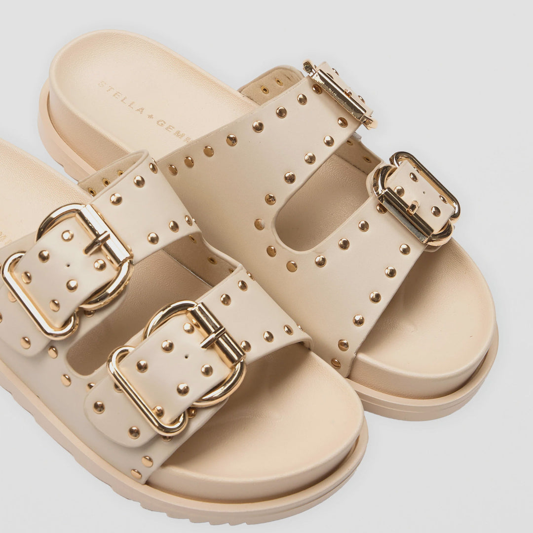 Beige sandals with gold buckles on a light gray background