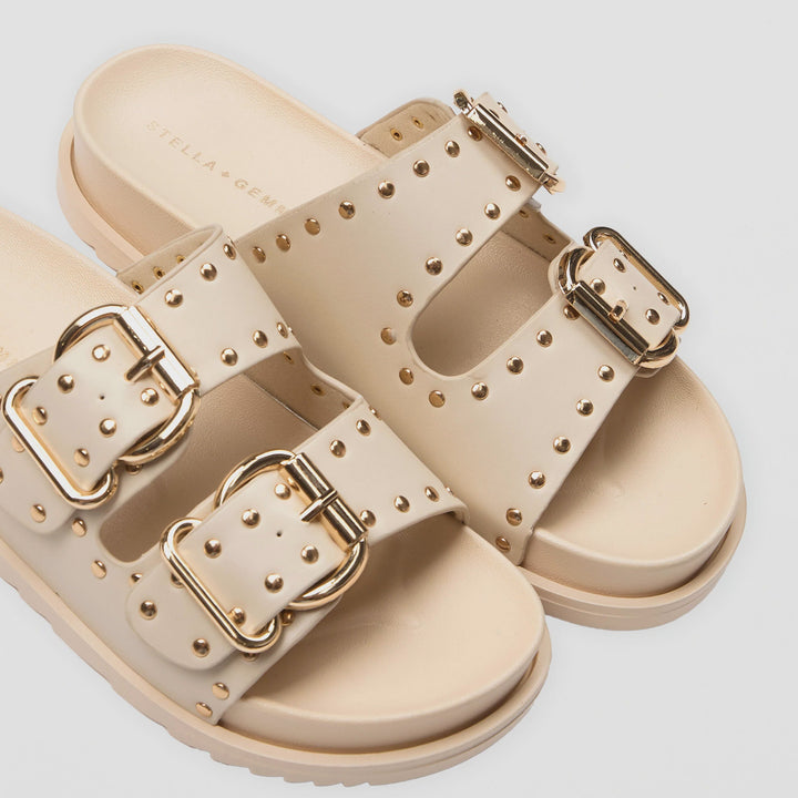 Beige sandals with gold buckles on a light gray background