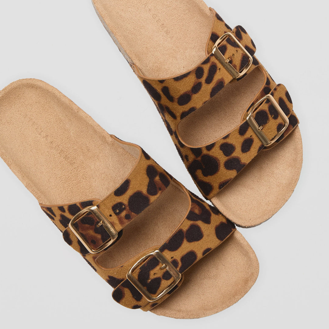 Leopard print sandals with brown buckles on a light gray background