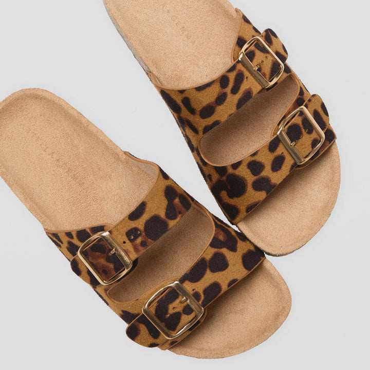 Leopard print sandals with brown buckles on a light gray background