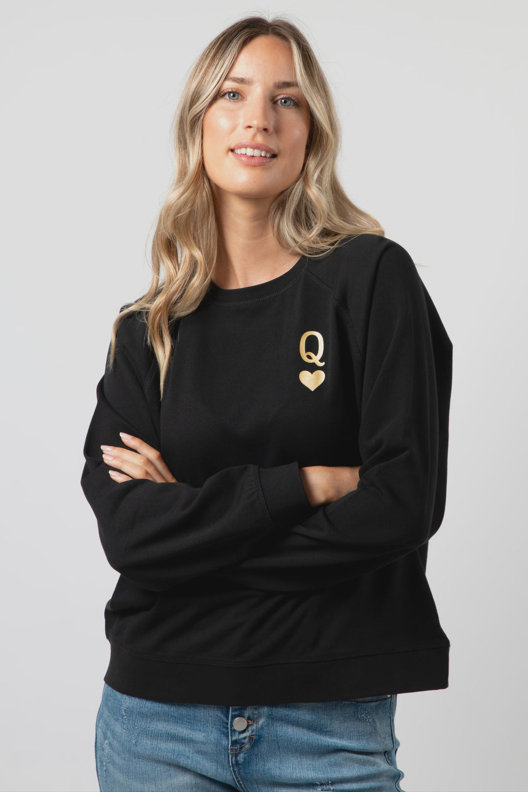 Woman wearing a black sweatshirt with a gold logo on a plain background