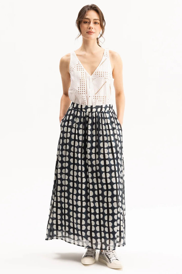 Woman wearing a white sleeveless top and black and white patterned skirt on a white background
