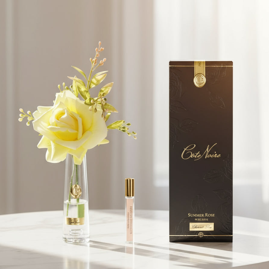 Set with a small vase of a cote noire yellow rose and a perfume bottle .
