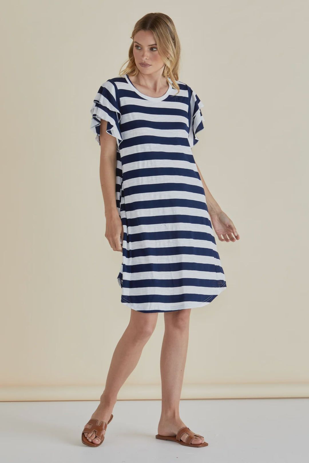 Woman wearing a blue and white striped dress against a beige background