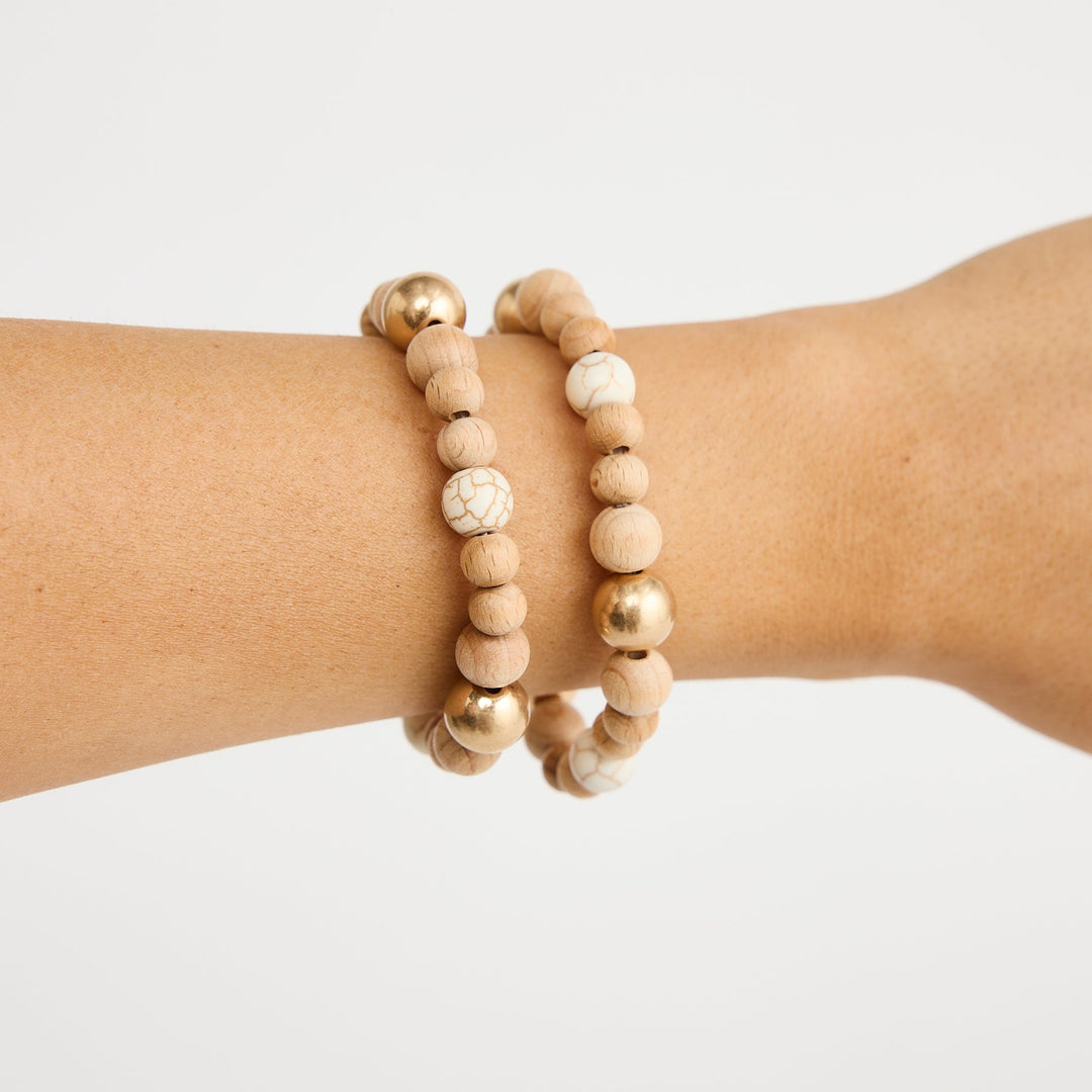 Two beaded bracelets on a wrist against a white background