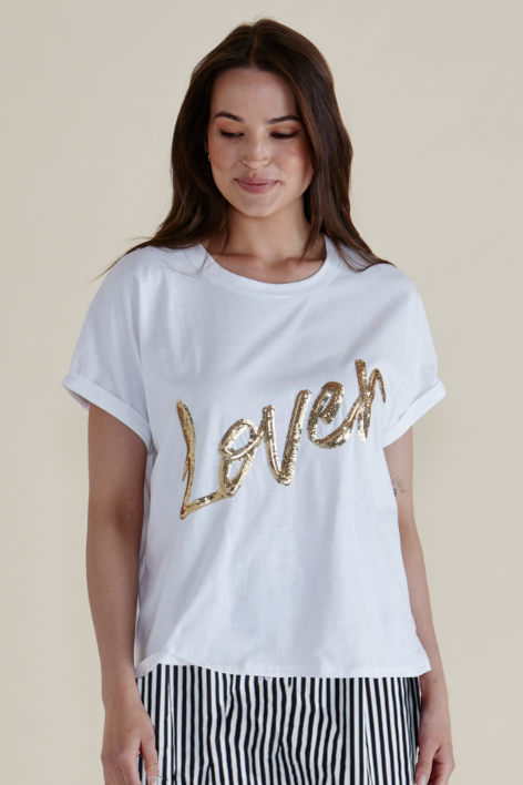 Woman wearing a white t-shirt with gold 'Love' text on a beige background