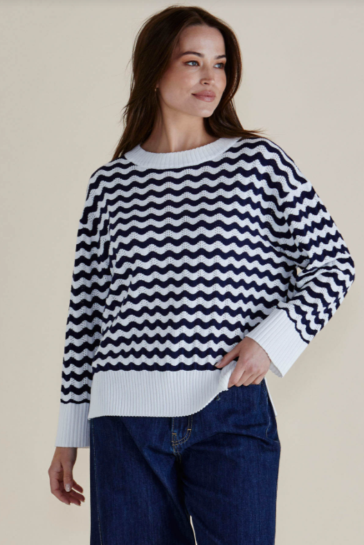 Woman wearing a navy and white striped sweater with a beige background
