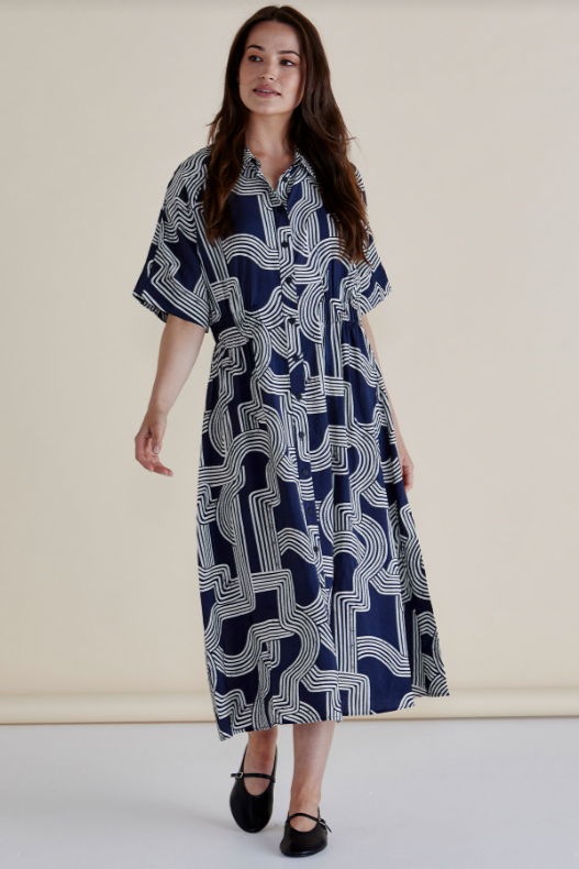 Woman wearing a blue patterned dress against a plain background