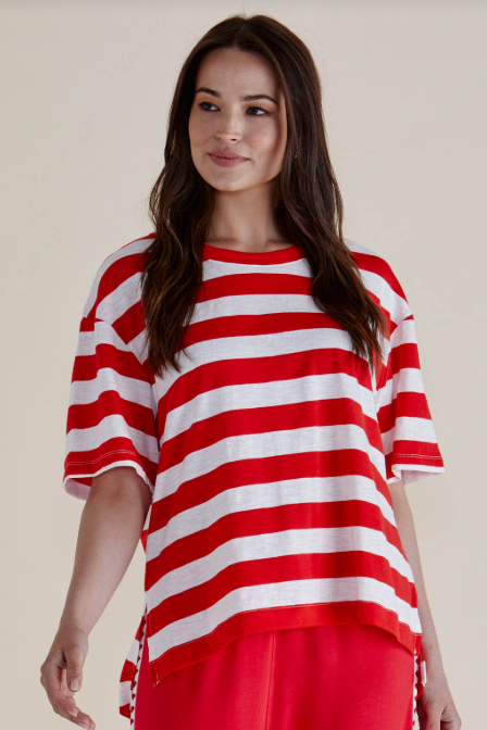 Woman wearing a red and white striped shirt with red pants on a beige background