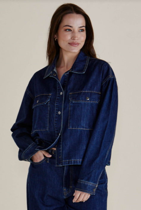 Woman wearing a blue denim jacket and pants on a plain background
