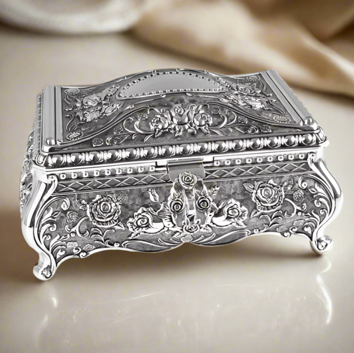 Decorative silver jewelry box with intricate designs on a white background
