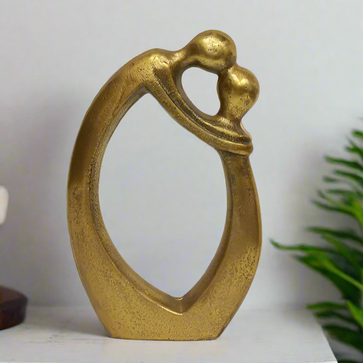 Gold decorative object shaped like a couple embracing on a white background