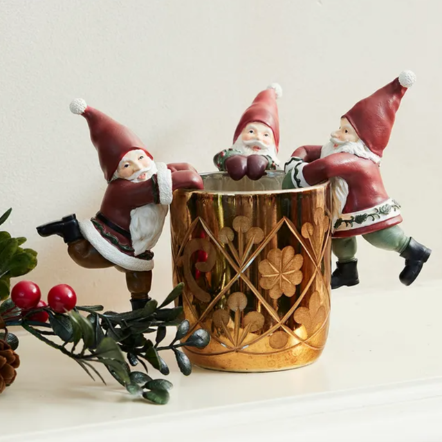 Three decorative gnomes around a wooden basket on a white surface with a light background