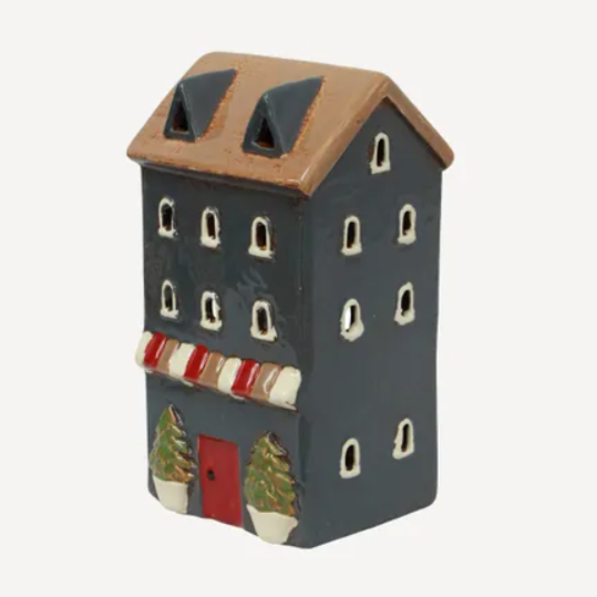 Small ceramic house-shaped ornament with a brown roof and red door on a white background