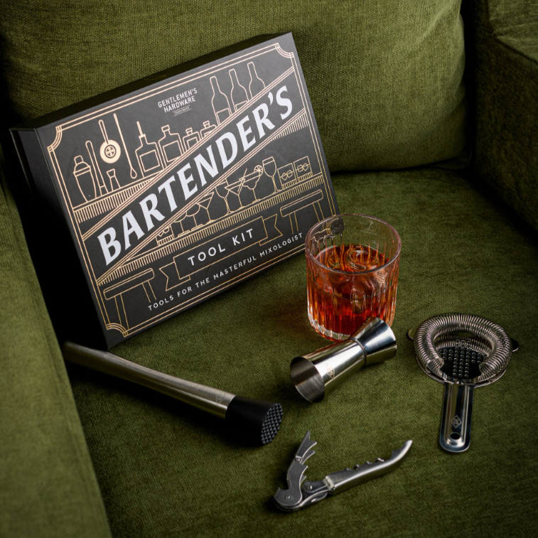 Bartender's tool kit with cocktail ingredients on a green couch