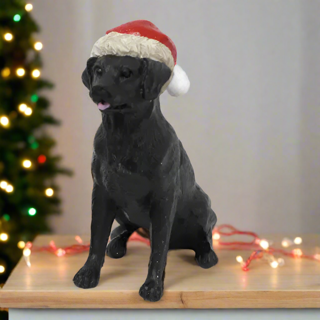 Black dog figurine wearing a Santa hat on a white background