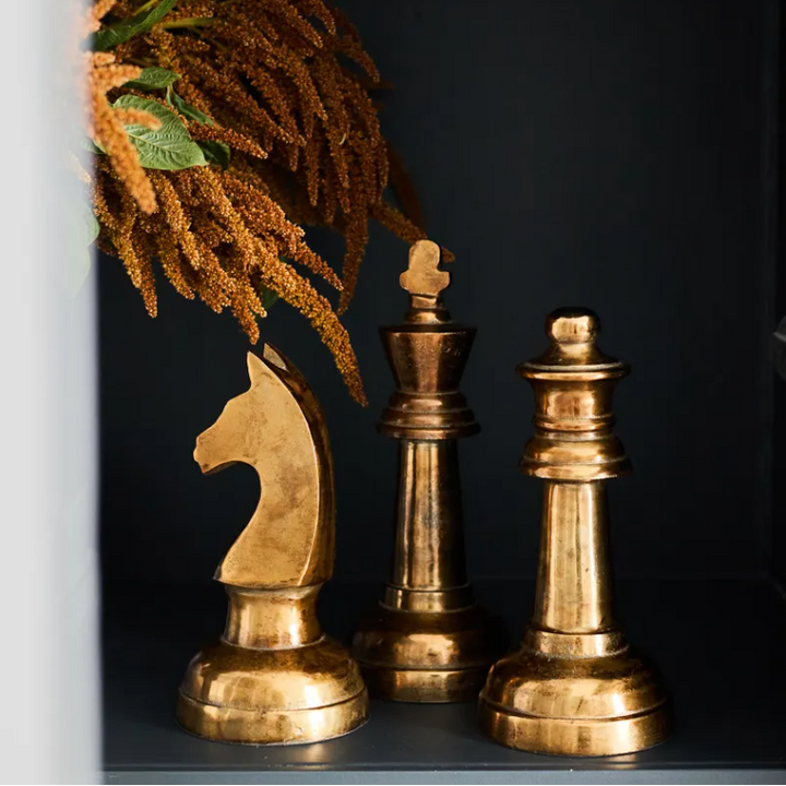Three gold decorative chess pieces on a dark surface with decorative elements.