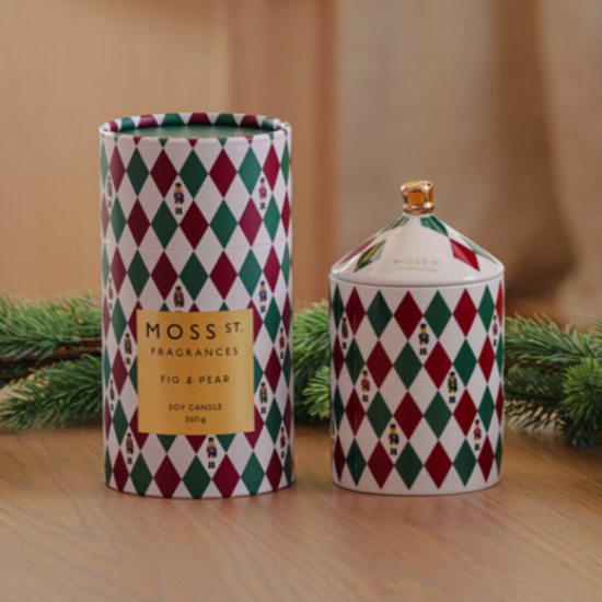 Two patterned MOSS ST candles on a wooden surface with a blurred background