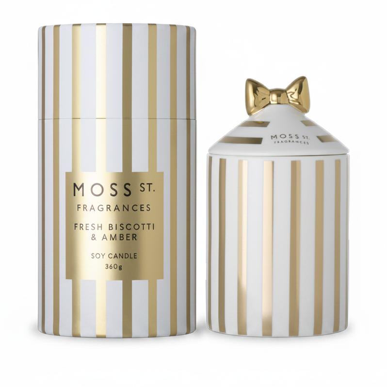 Moss St. Fragrances Fresh Biscotti & Amber soy candle set, featuring a tall cylindrical box and a smaller matching jar with a gold bow on the lid, both decorated with vertical gold and white stripes.