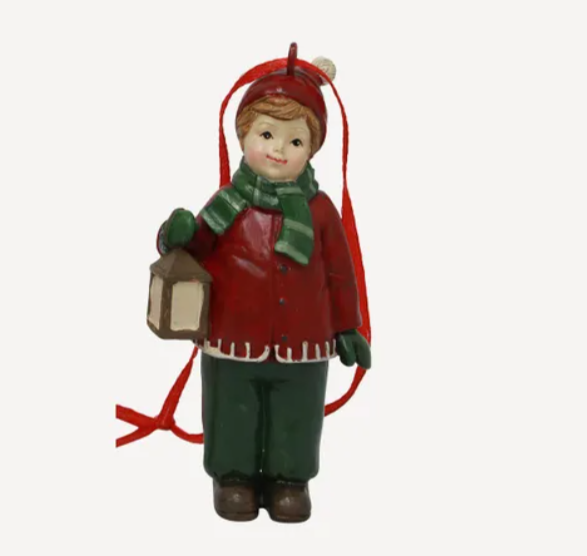 Christmas ornament of a boy in red sweater and green pants holding a lantern on a white background
