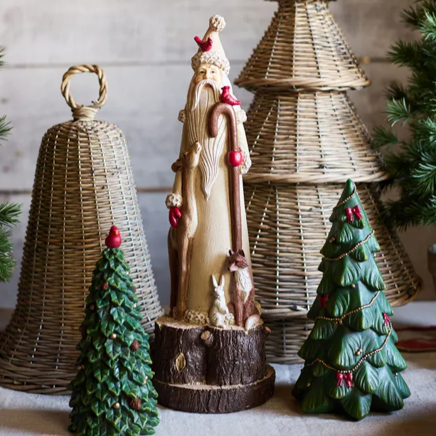 Decorative Christmas items including a Santa figure, wicker bell, and trees on a table.