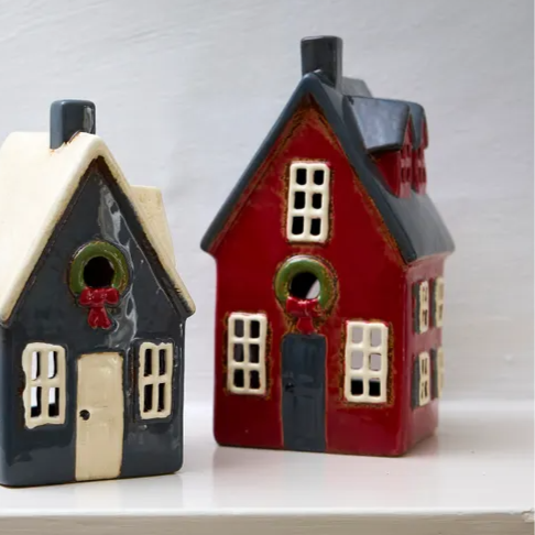 Two small house-shaped birdhouses on a white surface with a light gray background