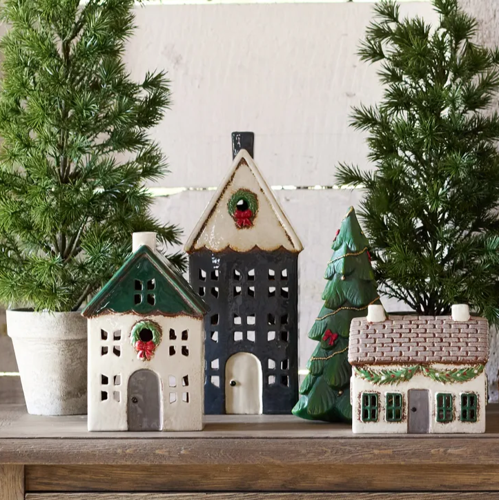 Decorative ceramic houses with Christmas trees on a wooden surface
