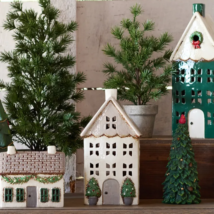 Decorative ceramic houses and Christmas trees on a wooden surface with a neutral background