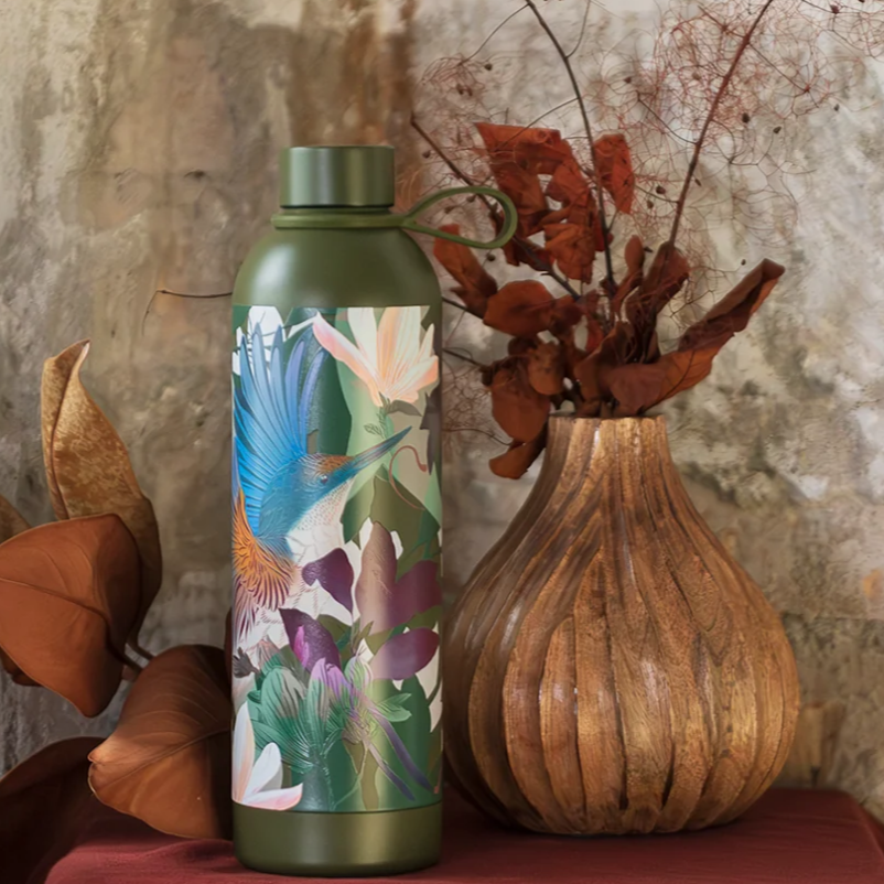 Green flox water bottle with floral design next to a wooden vase against a stone wall.