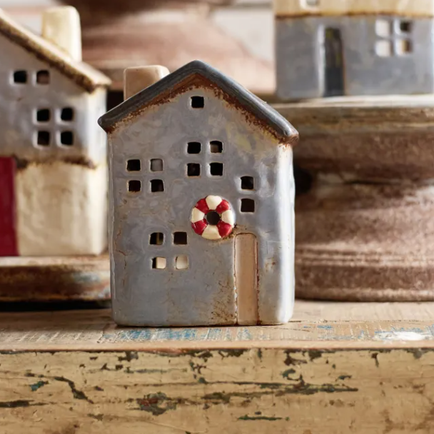 Small ceramic house with a red and white life buoy on a wooden surface