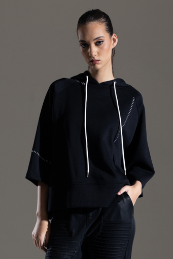 Person wearing a black outfit with white accents on a gray background