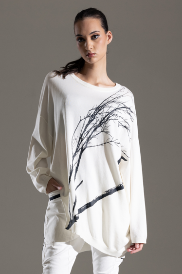 Model wearing a white outfit with black abstract design on a gray background