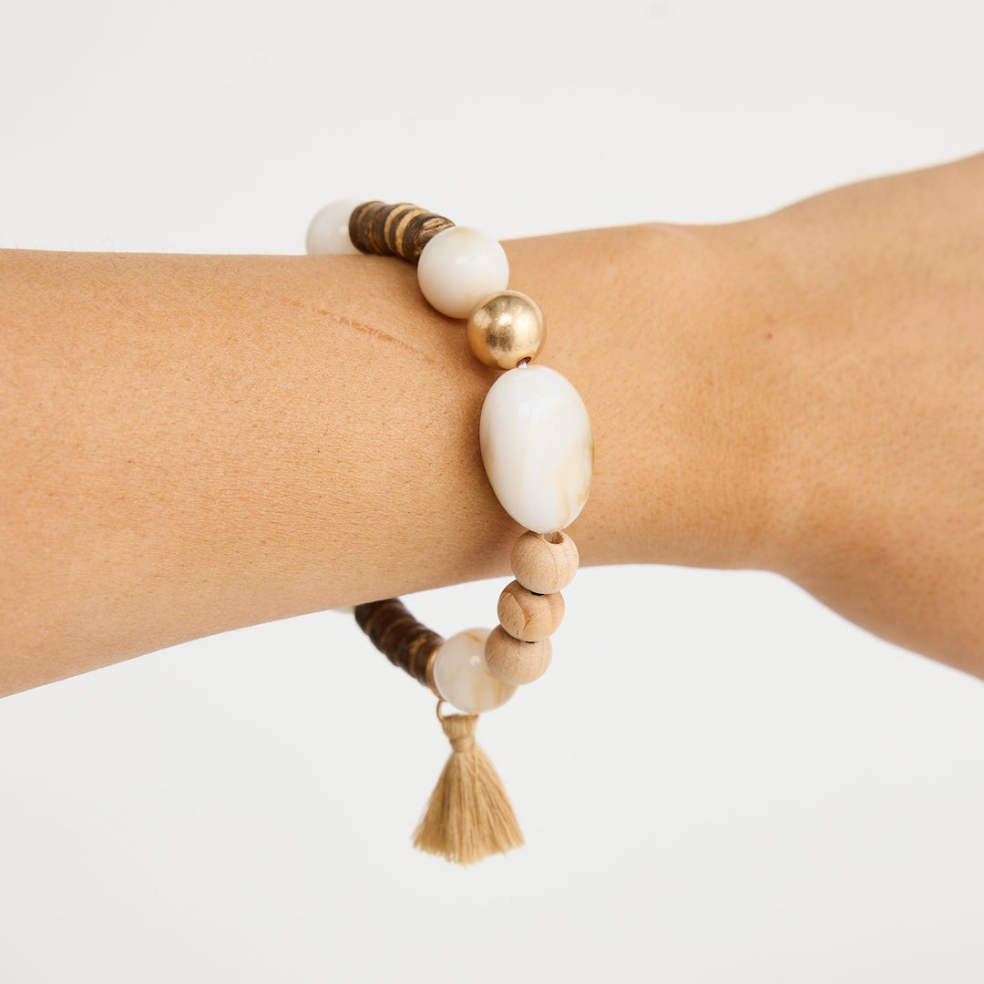 Beaded bracelet with a tassel on a wrist against a white background