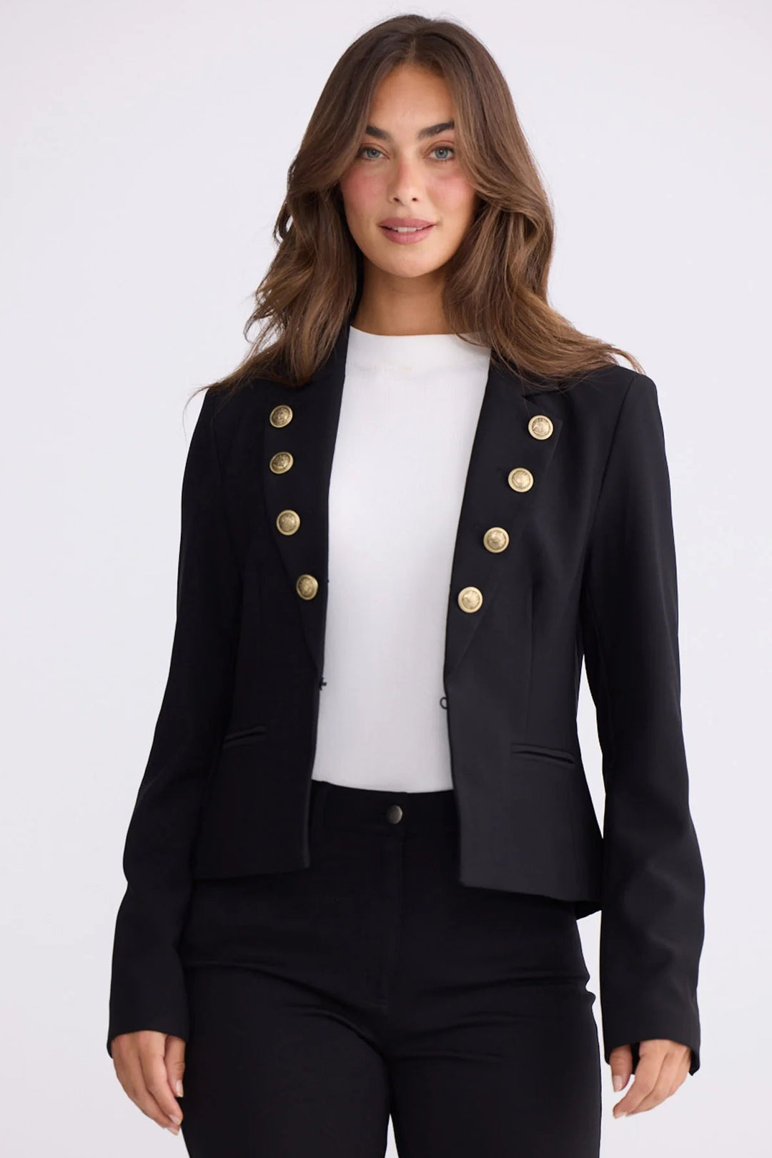 Woman wearing a black blazer with gold buttons on a white background