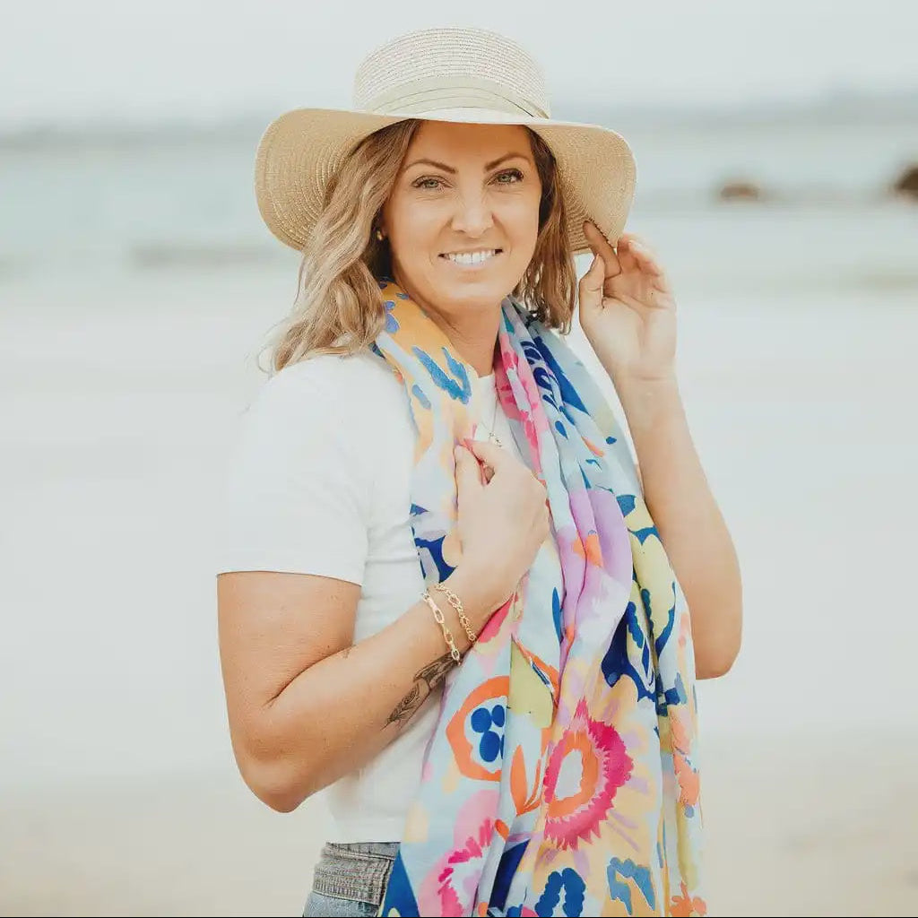 Woman wearing a colorful scarf and sun hat on a beach