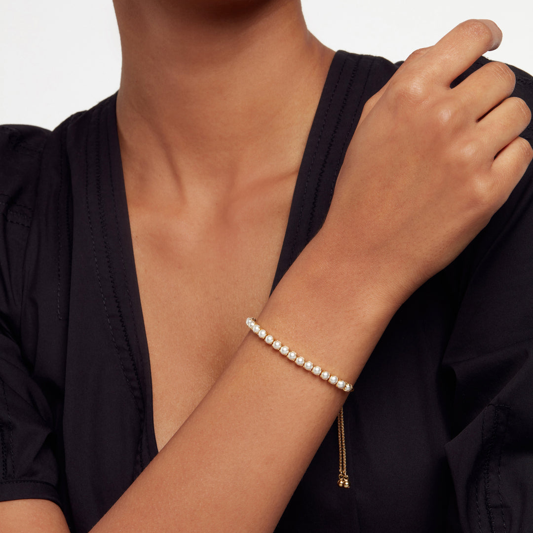 Woman wearing a Ted Baker pearl bracelet on a plain background