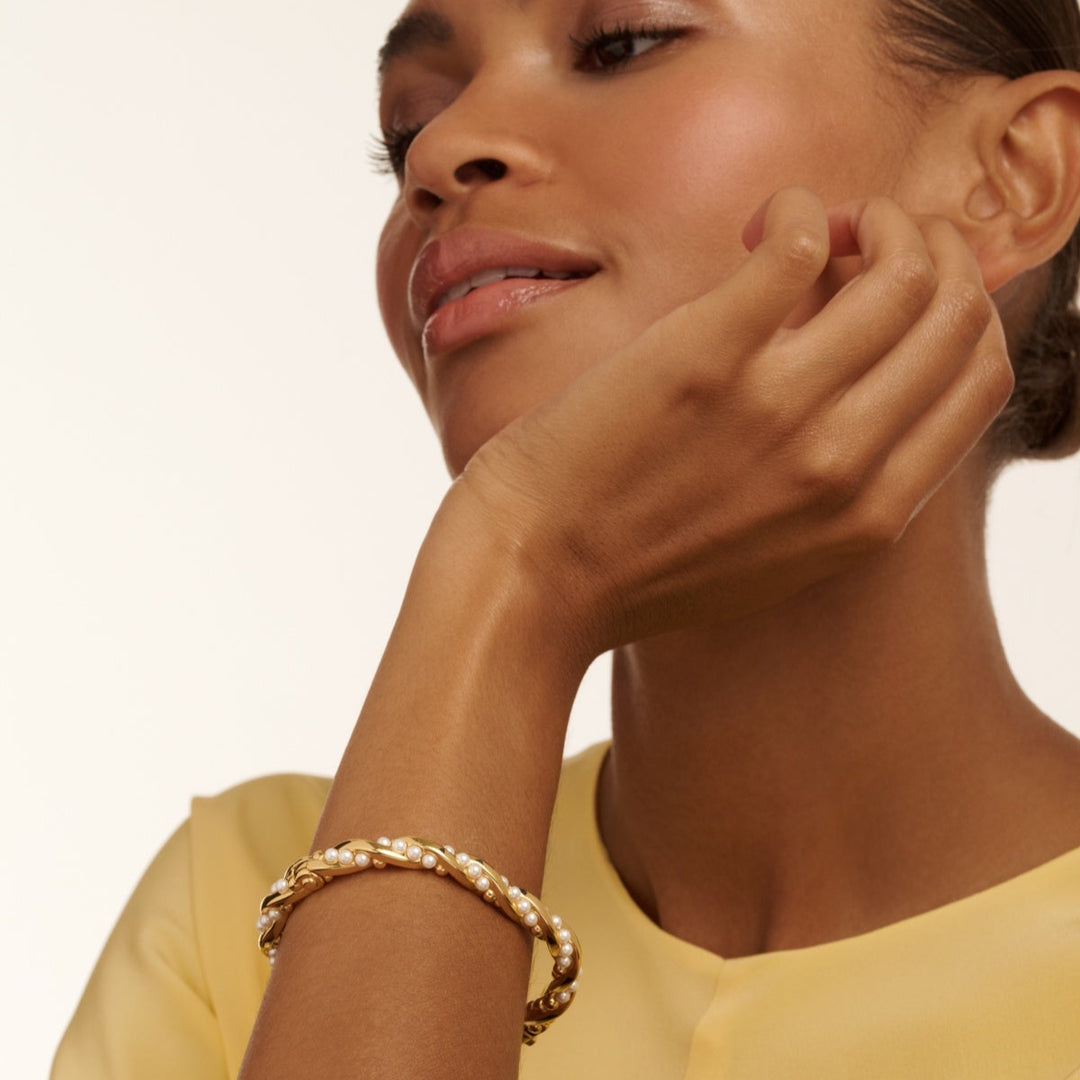 Woman wearing a gold bracelet on a beige background