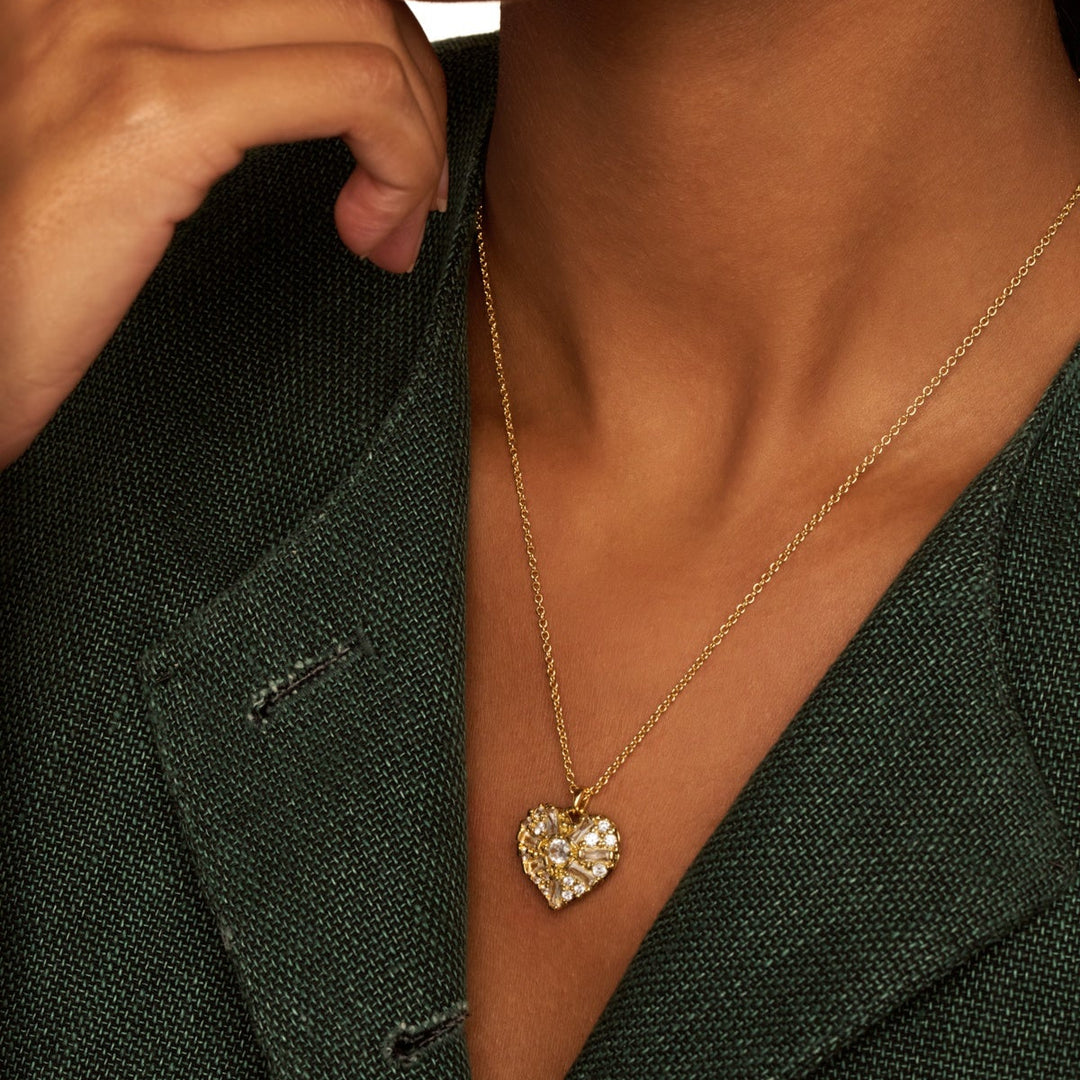 Heart-shaped necklace worn by a person in a dark suit